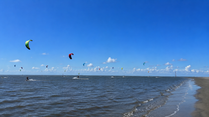 Kitesurfen in St. Peter-Ording – Wassersport an der Nordsee Kitesurfer auf der Nordsee vor dem Strand von St. Peter-Ording bei sonnigem Wetter und blauem Himmel.