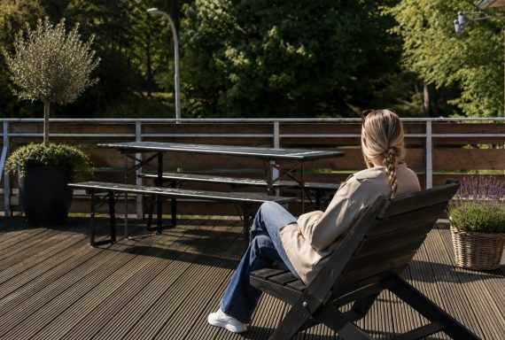 Entspannen & abschalten Eine Person sitzt auf einer Bank und blickt auf einen ruhigen Park mit Bäumen.