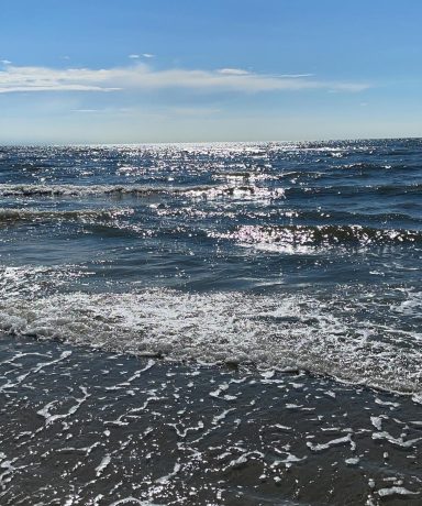 Nordsee und Strand in St. Peter-Ording Sanfte Nordseewellen am Strand von St. Peter-Ording unter blauem Himmel und glitzernder Sonne.