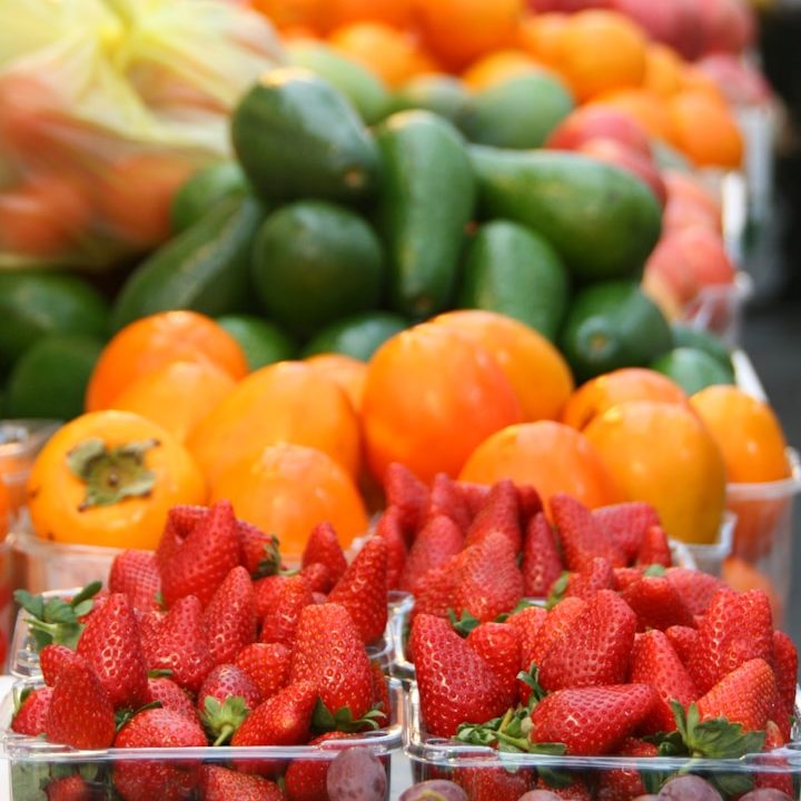 Obst und Gemüse Bunte Auswahl an frischen Früchten: Erdbeeren, Avocados und Kaki.