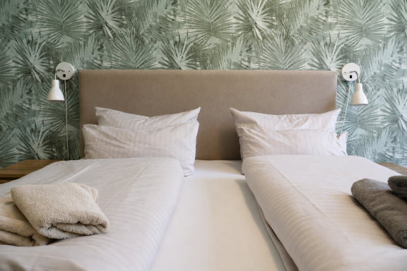 Hotelzimmer Zwei getrennte Betten mit weißen Bettwäsche und eleganter grüner Wandgestaltung.